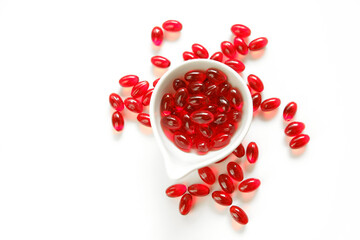Krill oil red gelatin capsules in white ceramic cup on a white background.omega fatty acids.Healthy...