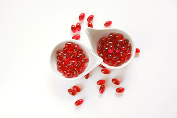 Krill oil red gelatin capsules in white ceramic cups set .omega fatty acids.Healthy eating and food supplements