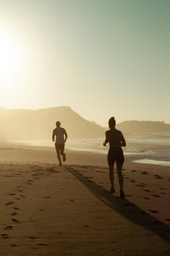 Pareja corriendo al amanecer en Playa Mermejita, Mazunte, Oaxaca