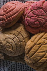 Traditional Mexican sweet bread called conchas, on a basket woven tablecloth.