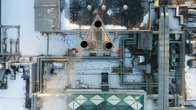 Heating, ventilation and air conditioning systems installed on a snow-covered rooftop. Smoke is coming out of the chrome-plated triple chimney. Aerial top down view