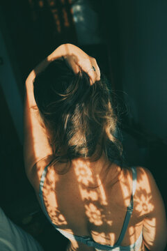 Back view of woman in gray bra with floral shadow on her