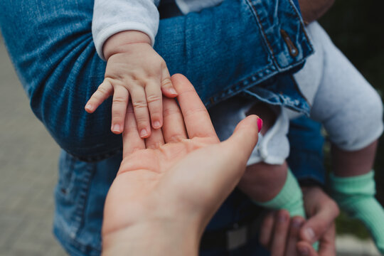 Cropped image of a person holding baby's hand who is held by the mother
