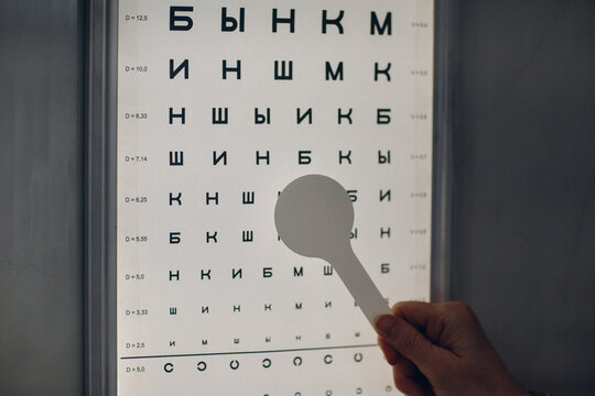 Cropped image of a person holding a pointer towards Snellen eye chart