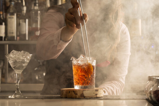 Cropped image of bartender adding orange slice to a cocktail