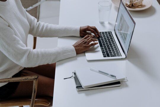 Cropped image of Black woman working on a laptop on light desk