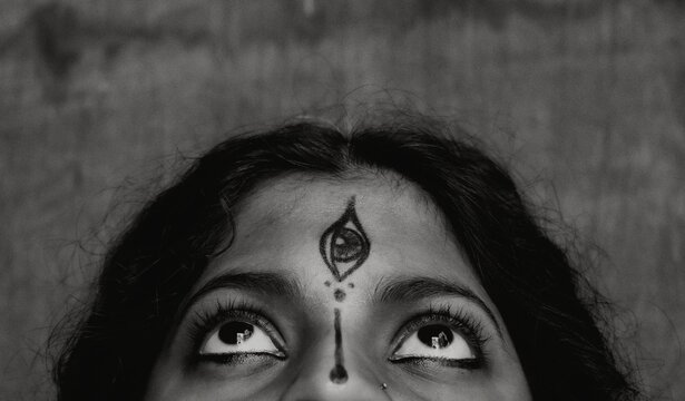 Grayscale photo of woman's forehead with Tilaka