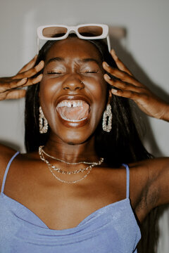 Smiling Black woman wearing gold jewelry and framed sunglasses