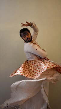 South Asian man in kathak dress dancing indoor