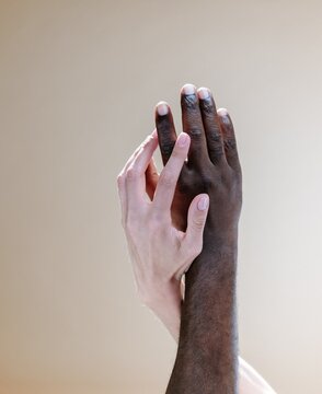Two hands romantically touching against pastel wall
