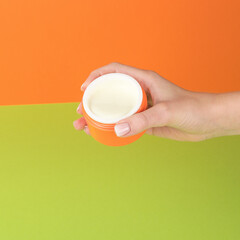 The girl's right hand holding an open jar of cream.