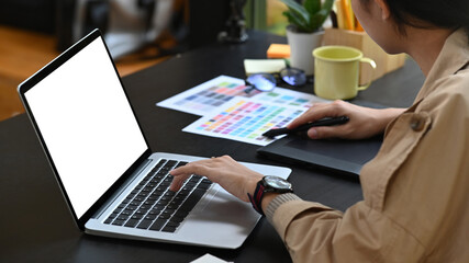 Creative woman working with laptop and color swatches.