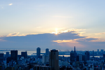 都市の夜明け。日の出の時間が過ぎるが、太陽は厚い雲に隠れていたが、ようやく雲の切れ目から顔を出す。神戸の山手ヴィーナスブリッジから撮影