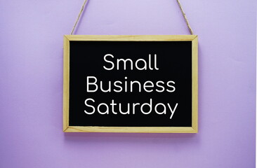 Small Business Saturday typography text on wooden blackboard hanging on purple background