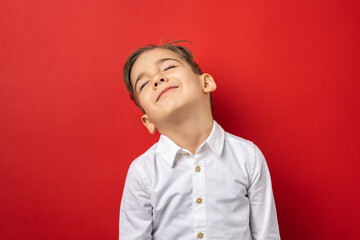 Obraz premium One small caucasian boy standing in front of red wall background with eyes closed sleepy and tired giving up concept
