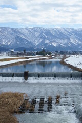 Obraz premium 雪国、富山県南砺市にある冬の山田川の風景、縦構図