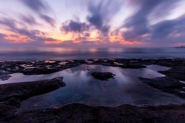 Twilight scenic sea landscape with beautiful shore, blurred flying dramatic blue clouds, amazing shoreline and sunset on background