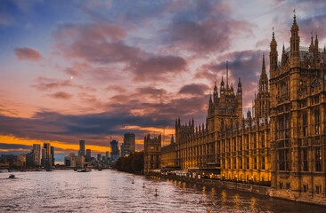 Fototapeta premium Beautiful view of Parliament buildings, Big Ben, and other buildings of City of Westminster at sunset , in London, England; buildings and clouds reflect in River Thames