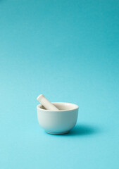 White pharmacy mortar and pestle on pastel blue background. Creative art concept. 