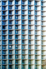 Many windows of a tall tower building with air conditioners close-up