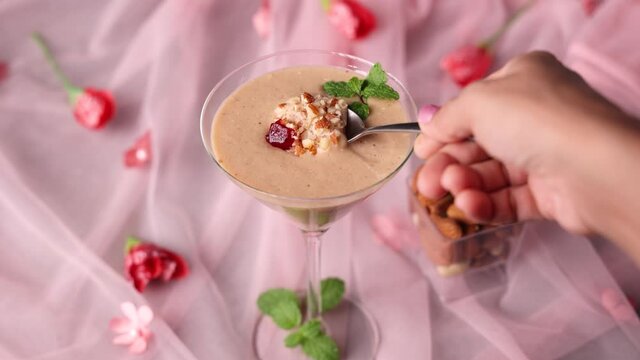 Kesar Badam milk shake Almond Saffron milk woman hand serving smoothie 4K video footage Kerala India. Kheer or North Indian traditional health drink Flavoured milk badam lassi served with dry fruit