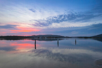 Soft and peaceful sunrise aerial waterscape with clouds and reflections