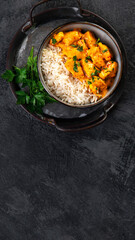 Indian butter chicken curry with basmati rice on dark background.