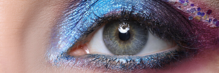 Closeup of beautiful female eye with bright shiny purple shadows