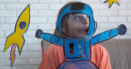 Astronaut traveler at home. A small astronaut try to travel in space from home on her glass picture. A little girl dreams of becoming an astronaut.