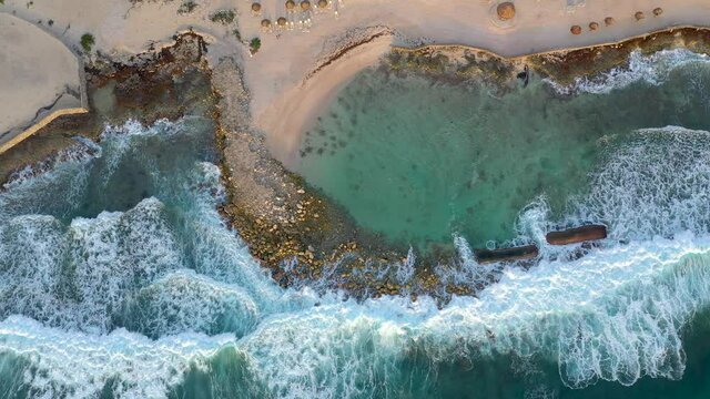 Wide top down view of resort in Tulum, Mexico. Waves are crashing as drone captures stunning view.