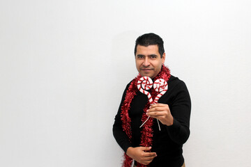Naklejka premium Latino adult man with Christmas hat shows Christmas decorations and decorations because he is ready to celebrate the holidays and the new year 