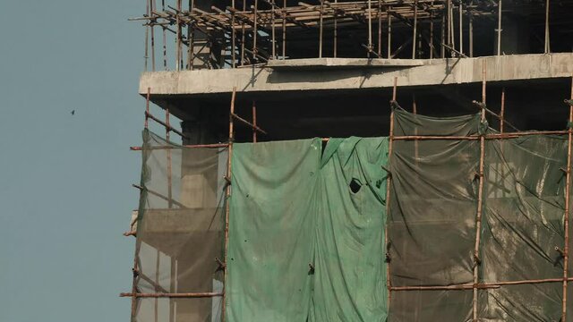 Large Sheeting Covering Construction Building With Bird Flying Past. Slow Zoom Out
