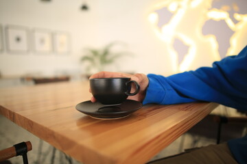 Close up profile of a man hands relaxing holding a cup of coffee in a wooden table at cafe