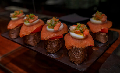 Traditional Spanish pintxos toast or tostada with smoked salmon and crab salad in a restaurant in San Sebastian Donostia, Basque Country, Spain