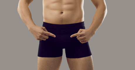 Underwear.Man fingers pointing at black classic shorts boxers in which he is dressed, isolated on...