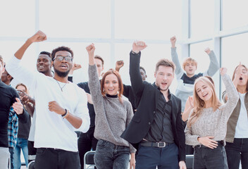 group of happy young people standing with their hands up