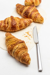 Kitchen knife and croissants on paper.