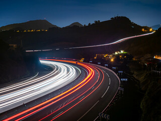 Trazos de luz dejados por el tráfico al circular por la noche por una autopista a su paso por un...
