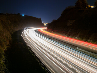 Trazos de luz dejados por el tráfico al circular por la noche por una autopista a su paso por un...