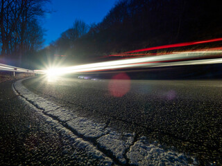 Trazas de luz dejadas por un vehículo al tomar una curva por la noche en una carretera de...