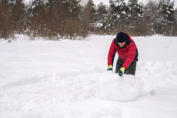 man makes a snowball for a snowman