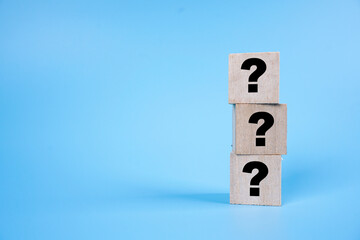 Question mark symbol on a wooden cube over blue background