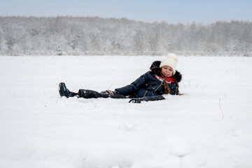 Fototapeta na wymiar happy girl lying in the snow, laughing and having fun