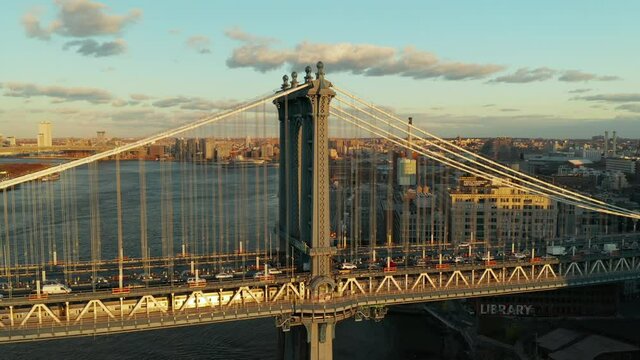 Busy double deck suspension bridge with various traffic in evening sun. Fly over and tilt down shot of Manhattan Bridge. Brooklyn, New York City, USA