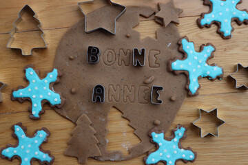 Bonne annèe . Gingerbread Cookie dough letters on wooden table with festive cookie cutters and glazed cookies - obrazy, fototapety, plakaty