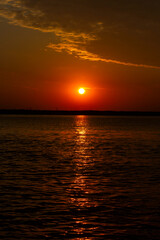 Dawn on the Volga River, the sun rises from the horizon and beautifully illuminates the clouds with red light, a sunny path on the water