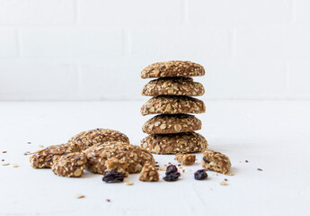 a stack of homemade oatmeal cookies with raisins, sesame, flax seeds stacked on a white table...