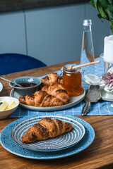 croissants with jam and honey on a wooden table.