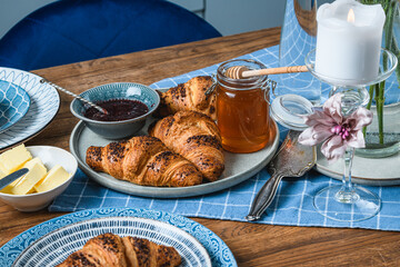 croissants with jam and honey on a wooden table.