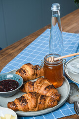 croissants with jam and honey on a wooden table.